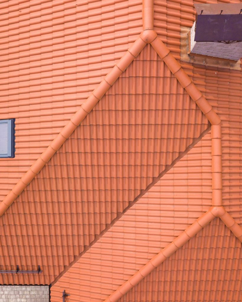 Aerial top view of house with metal shingle roof, brick chimneys and attic windows.